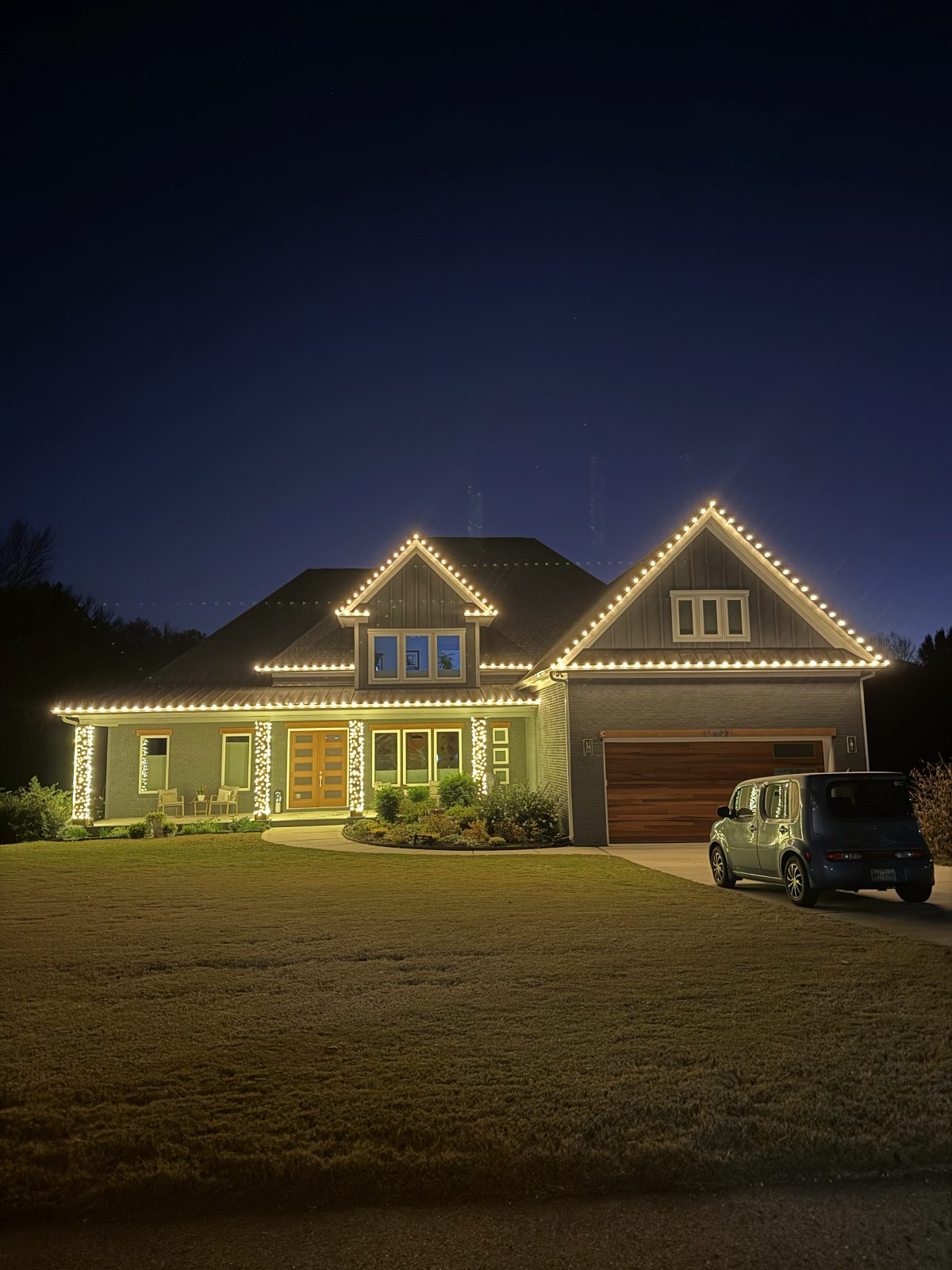 Craftsman home in Raleigh, NC with warm white lights tracing the roofline peaks and porch columns wrapped in Christmas lights