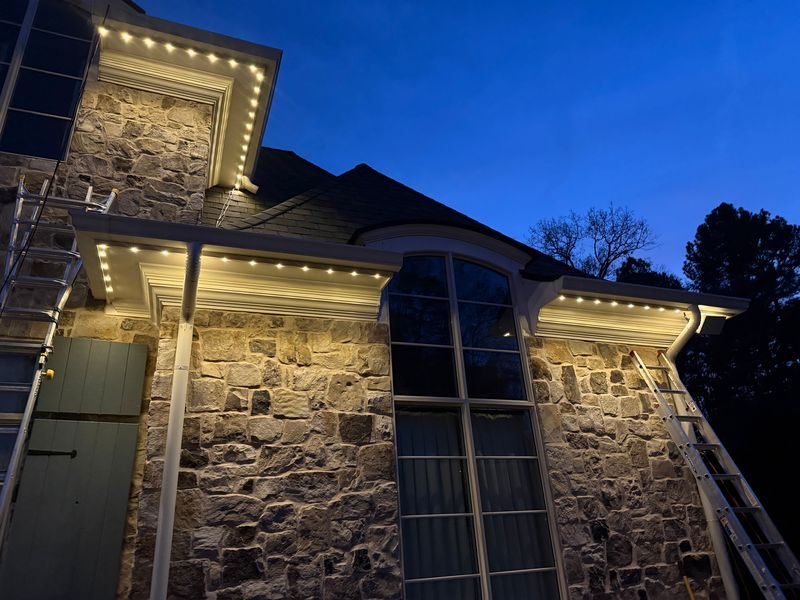 Close-up of track-mounted permanent LED lighting installed under the eave of a stone home